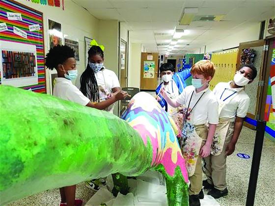 Students paint a dinosaur at Odom Academy that will be displayed at the Texas Energy Museum's Dinosaur Day.