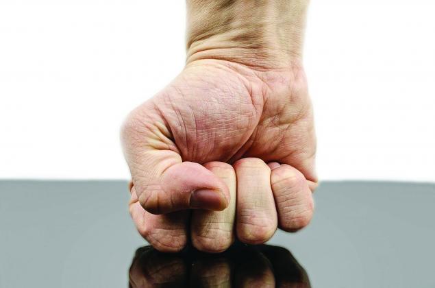 A fist against a table with a white background.
