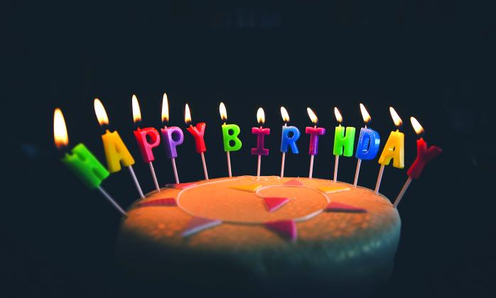 A photo of a birthday cake with candles spelling ' Happy Birthday' throughout 