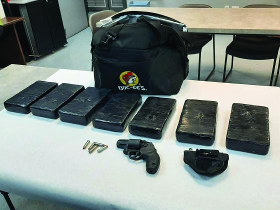 A photo of several packages of cocaine next to a bag with a buc-ee's logo bag.