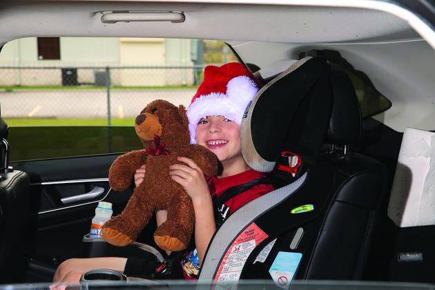 A young attendee to Bicycles and Bibles holds up a teddy bear while wearing a Santa hat at Bicycles and Bibles