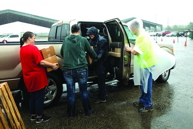 volunteers help load items into vehicles during rainfall at Bicycles and Bibles