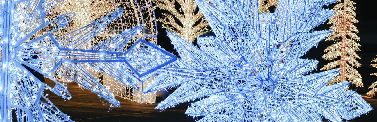 Phot of lighted snowflakes, trees and canopies with Christmas lights on them.