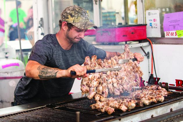 A food worker flips a row of kababs at the South Texas State Fair