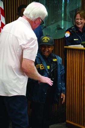 Retired FBI agent and 100 Club of southeast Texas Vice President Zack Shelton offers DJ a windbreaker from his days in the Bureau
