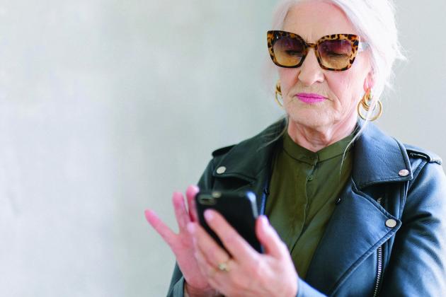 An older woman uses a cell phone.