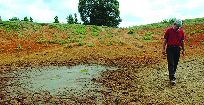 A person walks next to dried ground