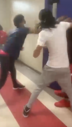 A screenshot depicts two students punching another who is off camera.