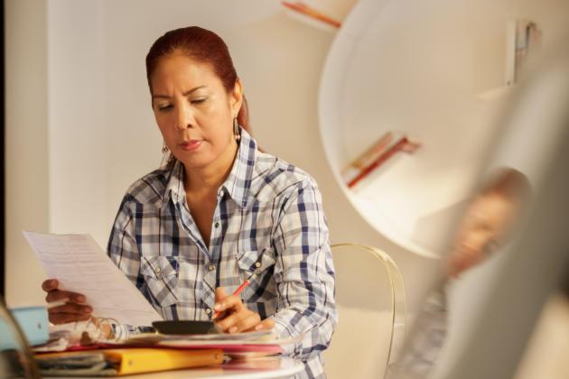 A woman looks over electric bills 