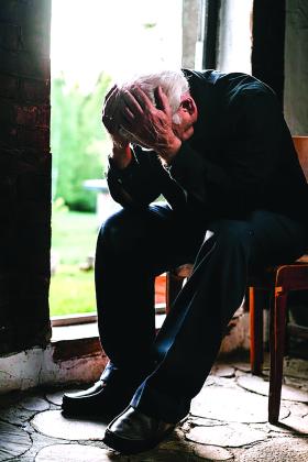 An older man sits in distress