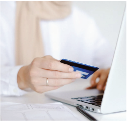 A person holds a credit card while using a laptop