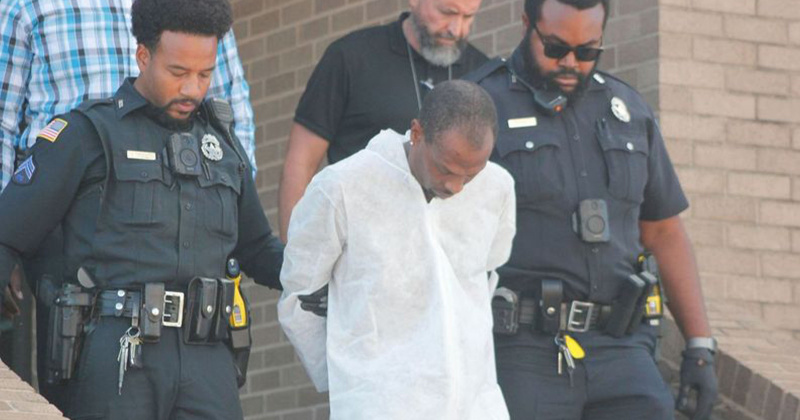 Beaumont Police Department officers escort Howard Celestine from police headquarters to a patrol unit.