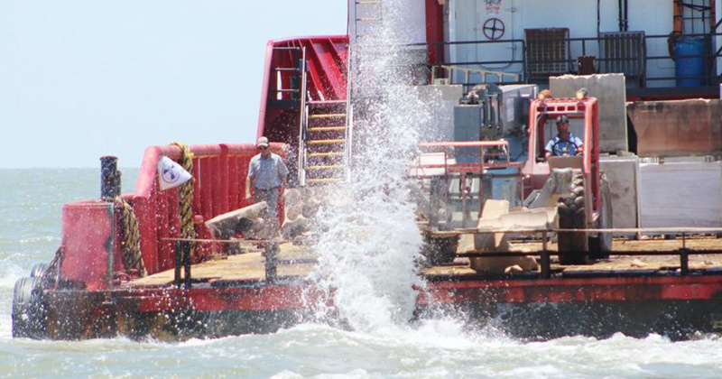 Crews dump obsolete and metal pieces to contruct an artificial reef.